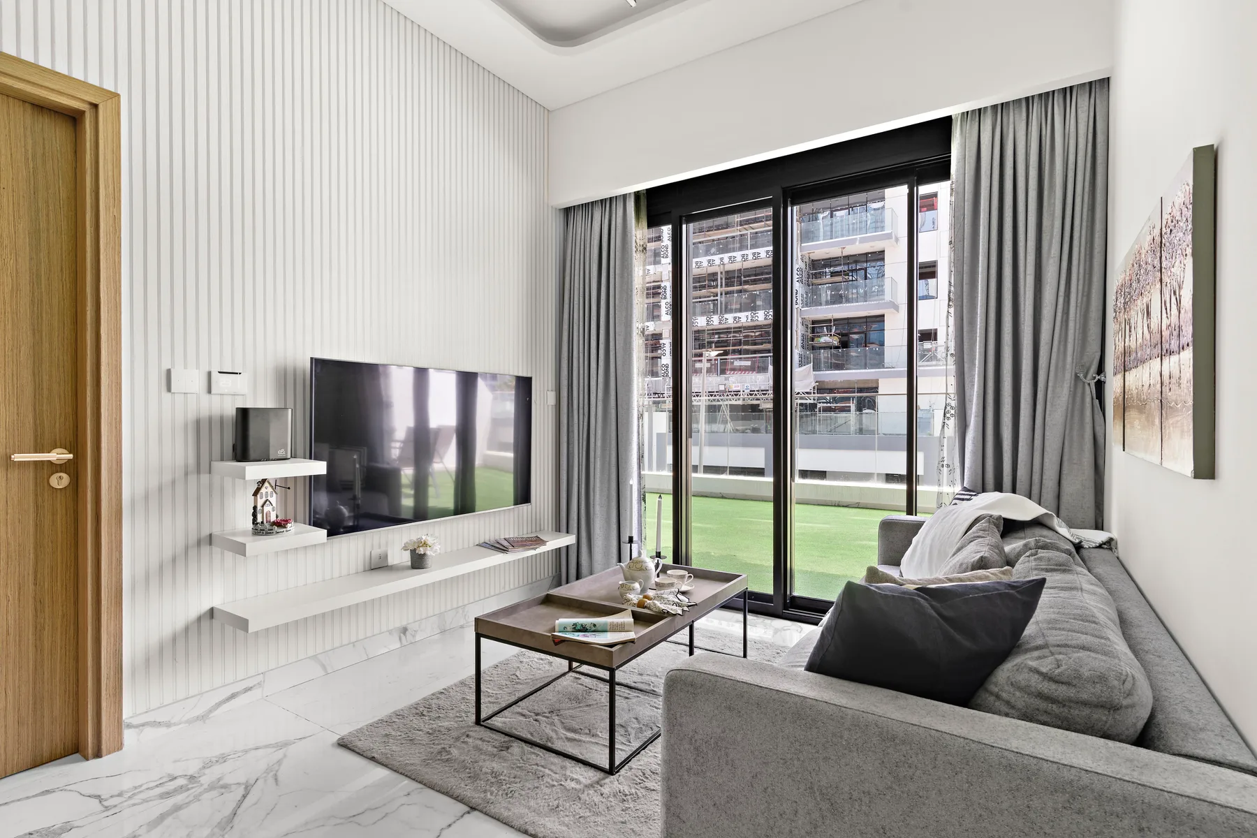 A modern living room with seating, a coffee table, and large windows.