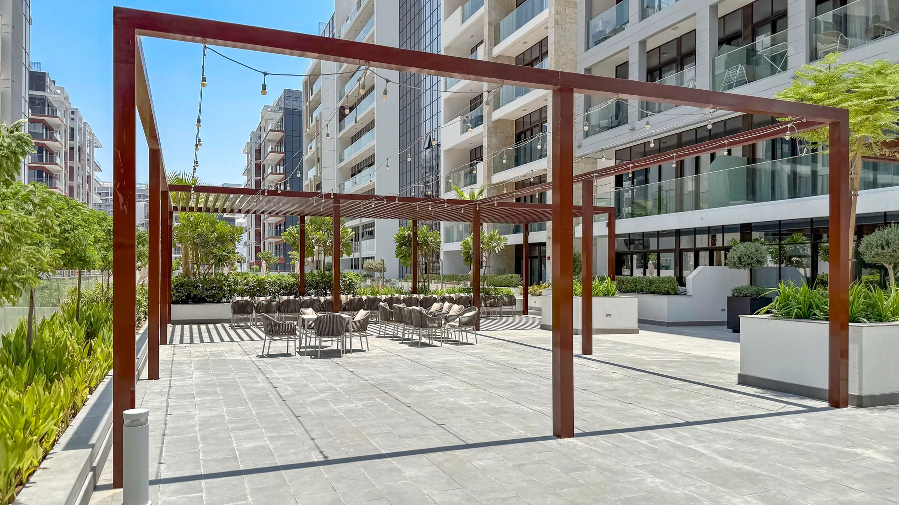 An outdoor courtyard with paved walkways, seating, and modern buildings.