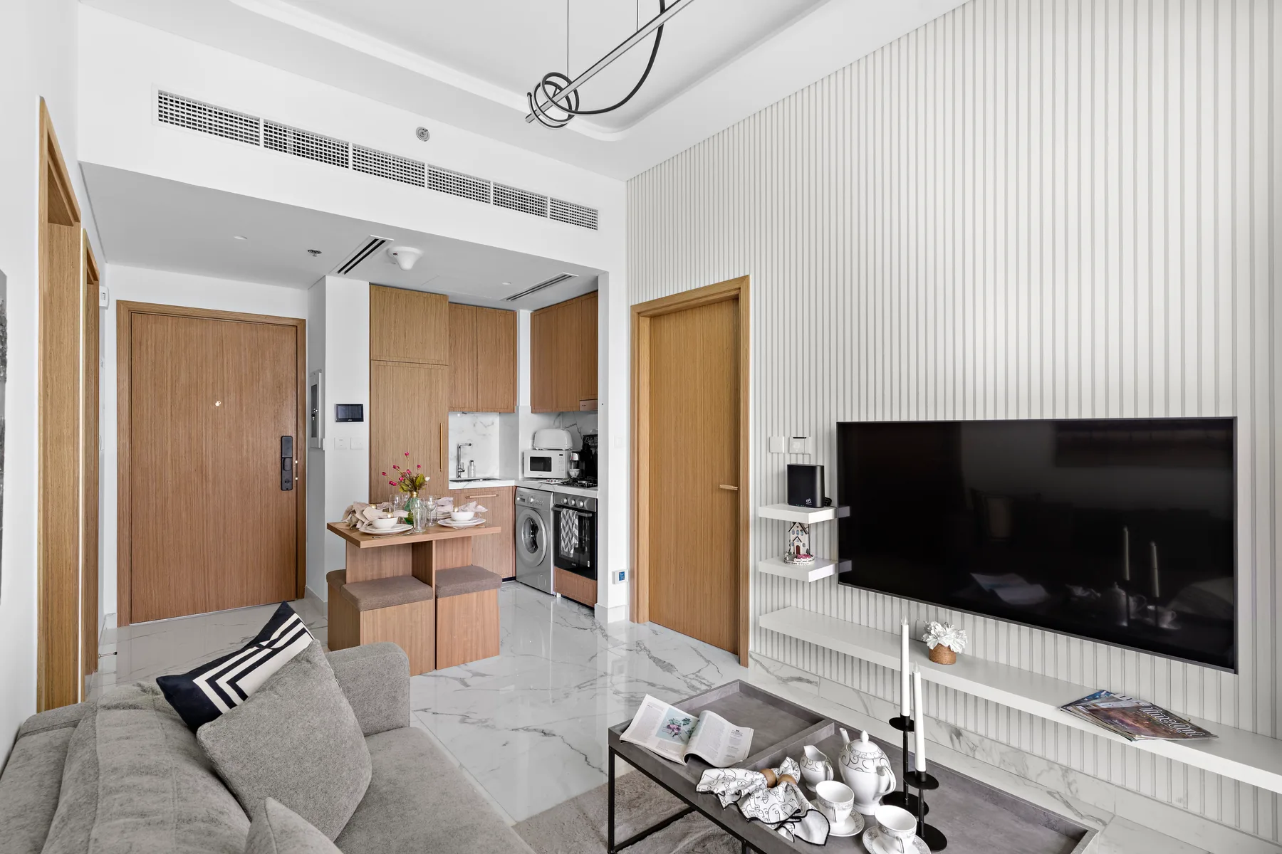 A bright living room with a gray seating area and a large television.
