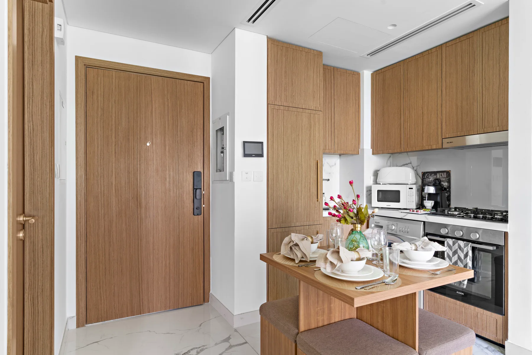 A modern kitchen and dining area with wood cabinetry and a set table.