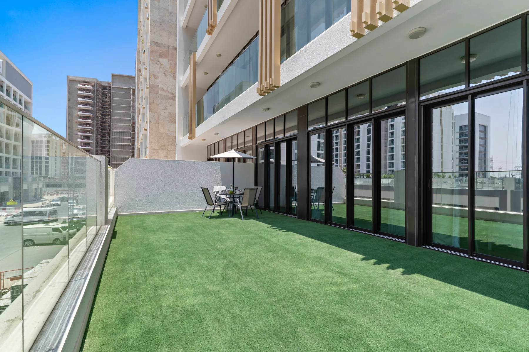 A rooftop terrace with green turf, glass railings, and outdoor seating.