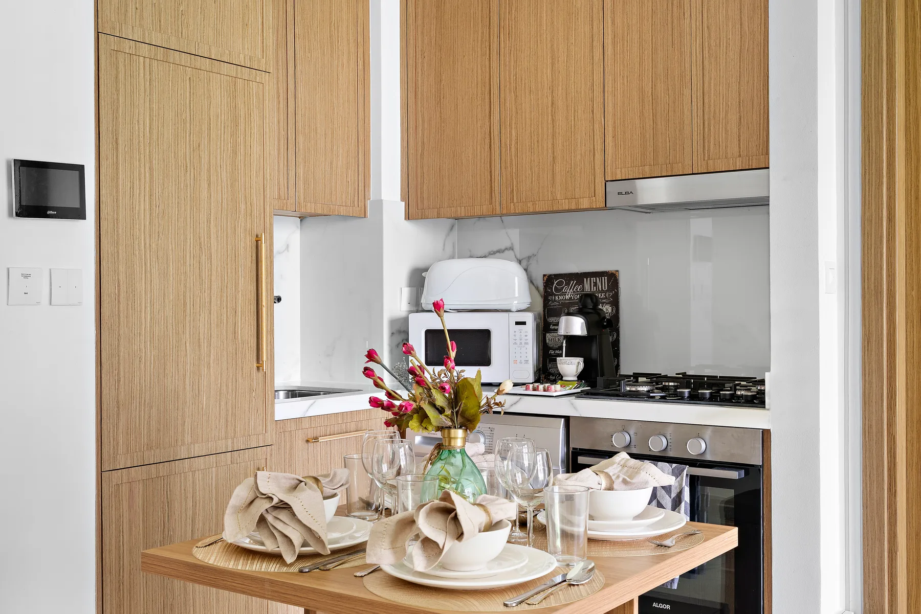 A bright kitchen and dining area with wooden cabinets and a table set for a meal.