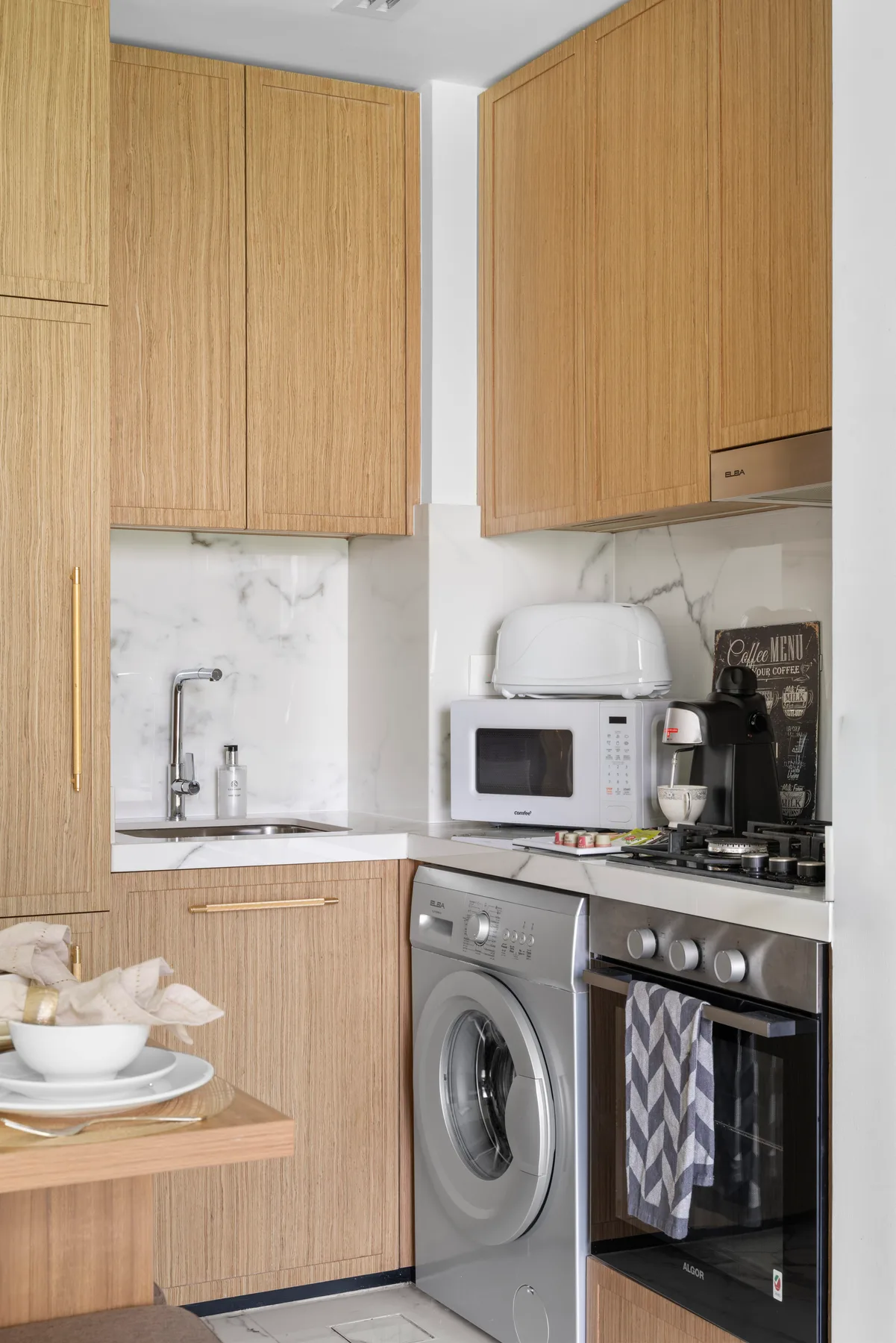 A compact kitchen with wood cabinetry, a sink, and cooking appliances.
