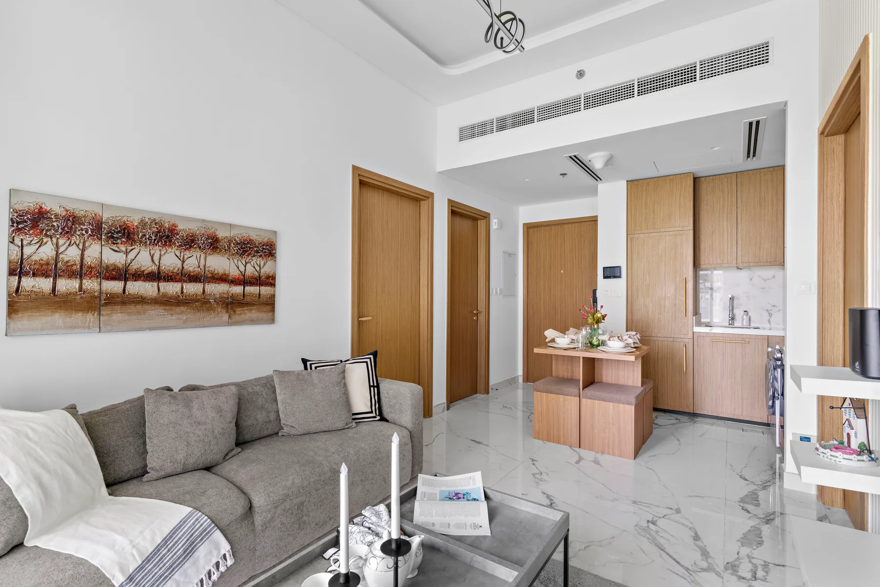 A bright living room with a gray seating area and an open kitchen.