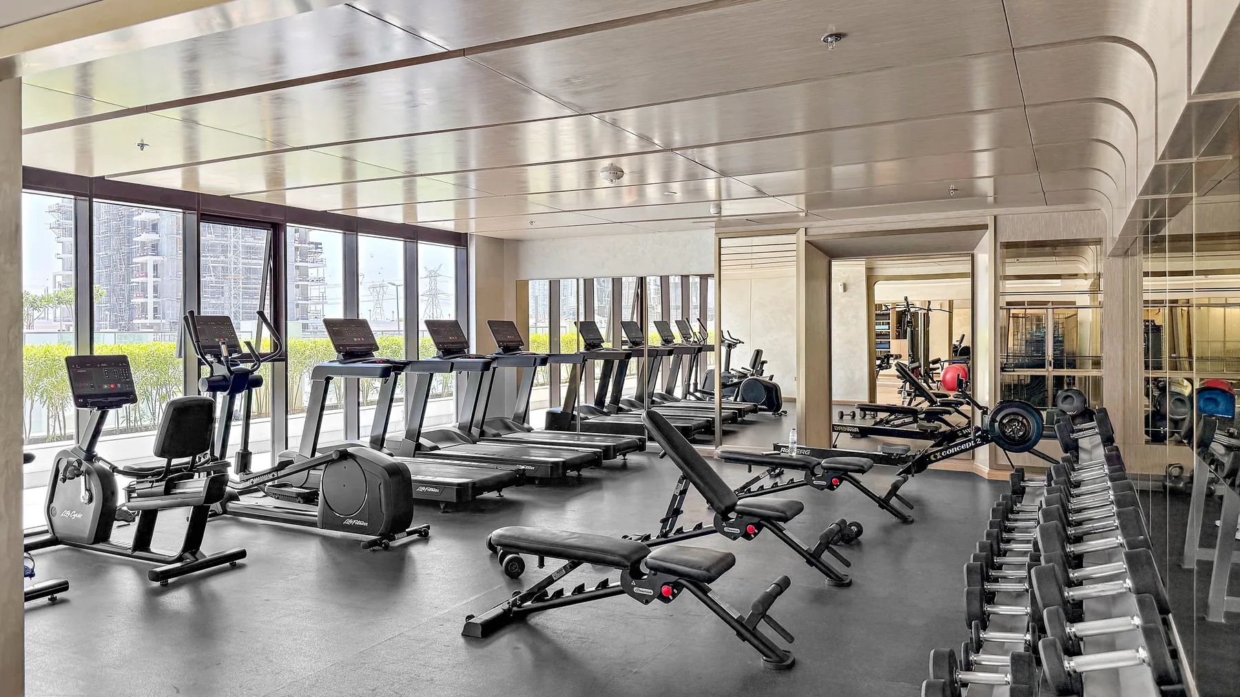 A fitness room with treadmills, exercise bikes, and weight-training equipment.