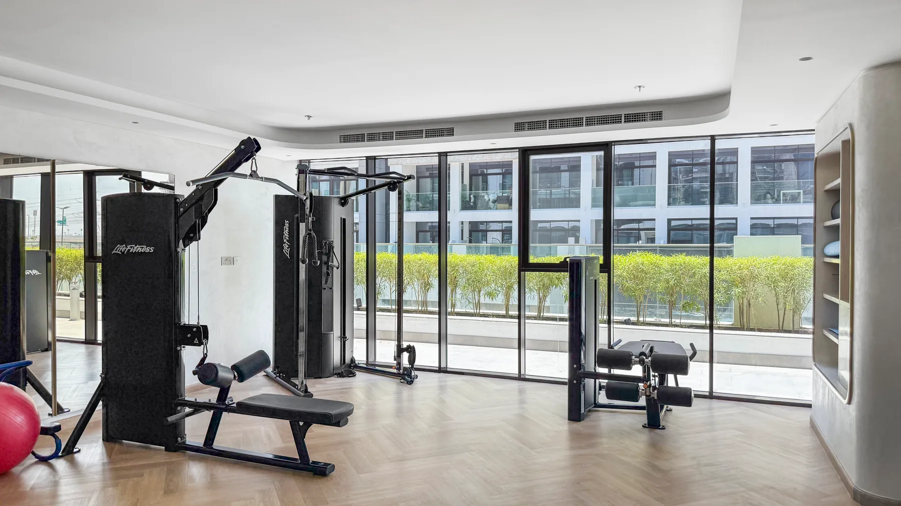 A gym with exercise machines beside floor-to-ceiling windows.