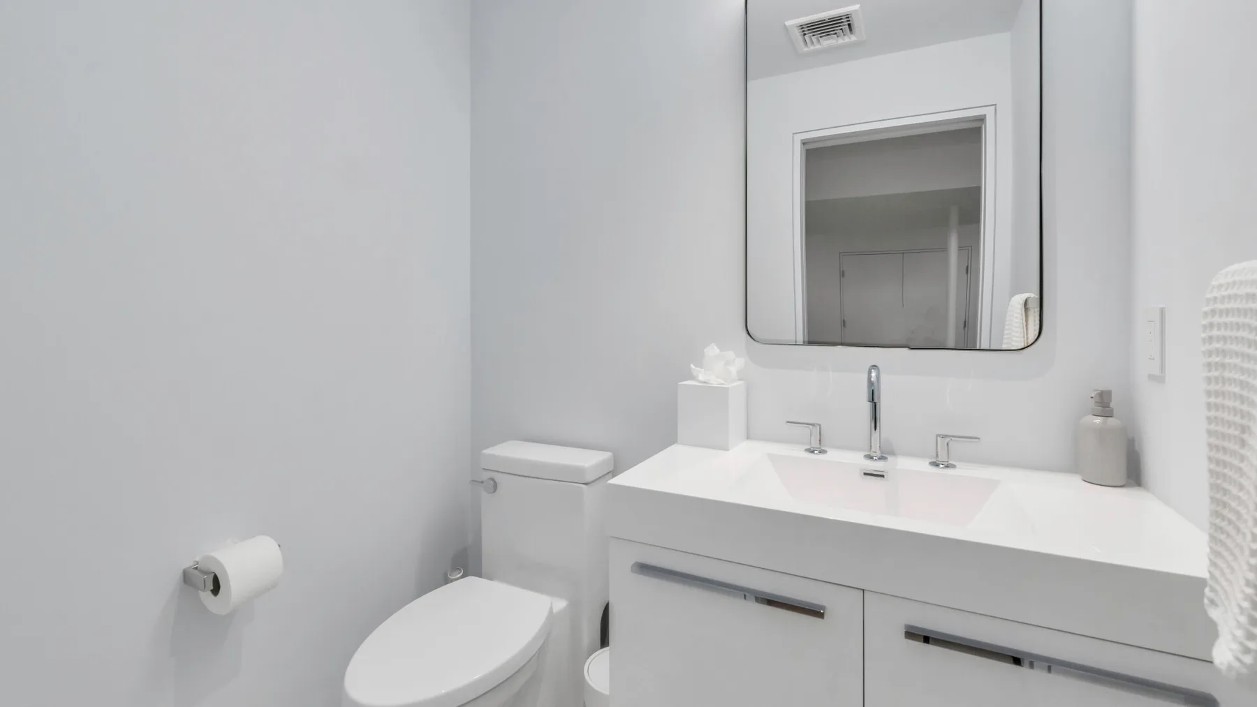 Un baño luminoso con un lavabo amplio, espejo e inodoro.