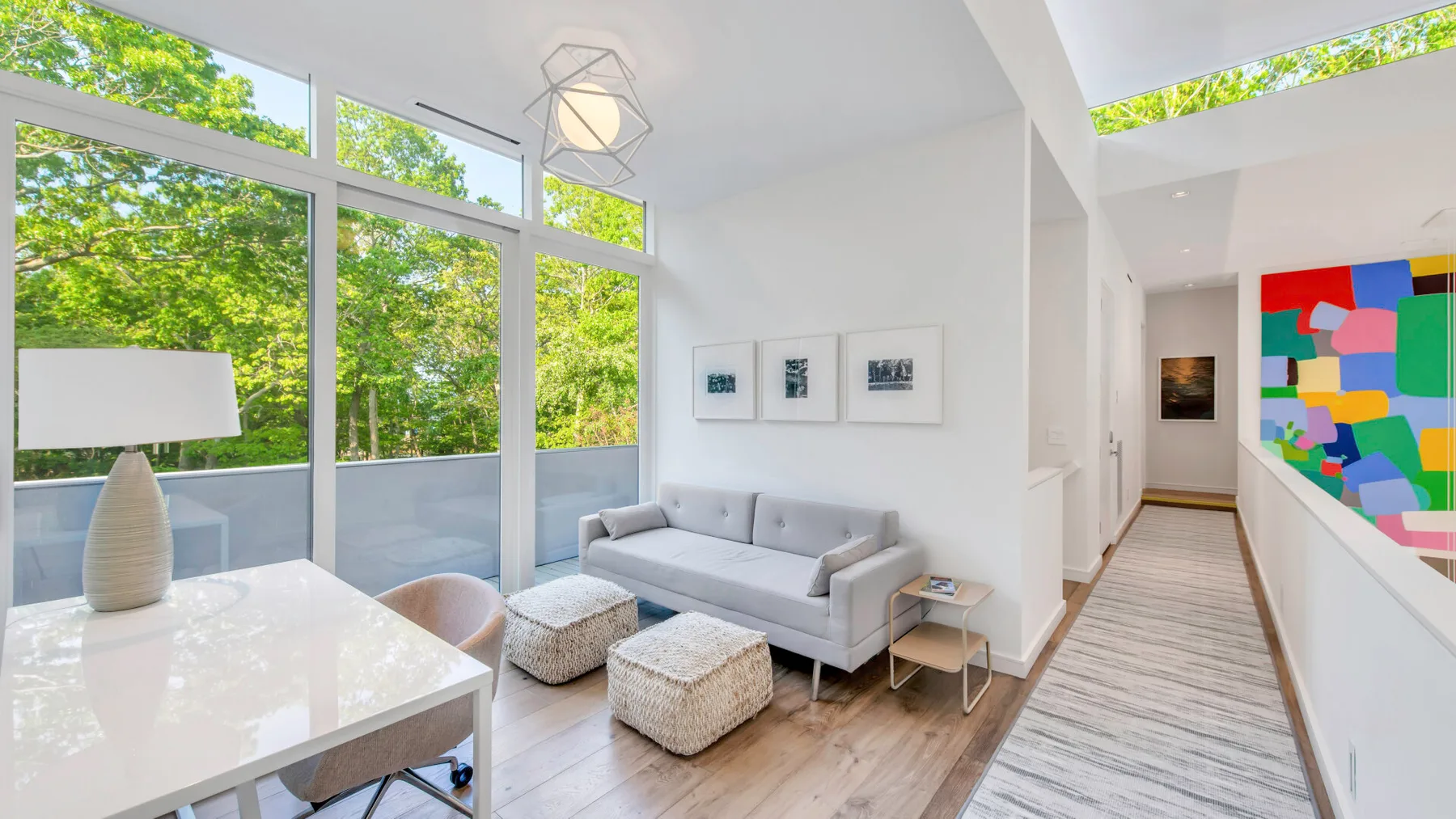 Una sala luminosa con asientos junto a grandes ventanales que dan a árboles frondosos.