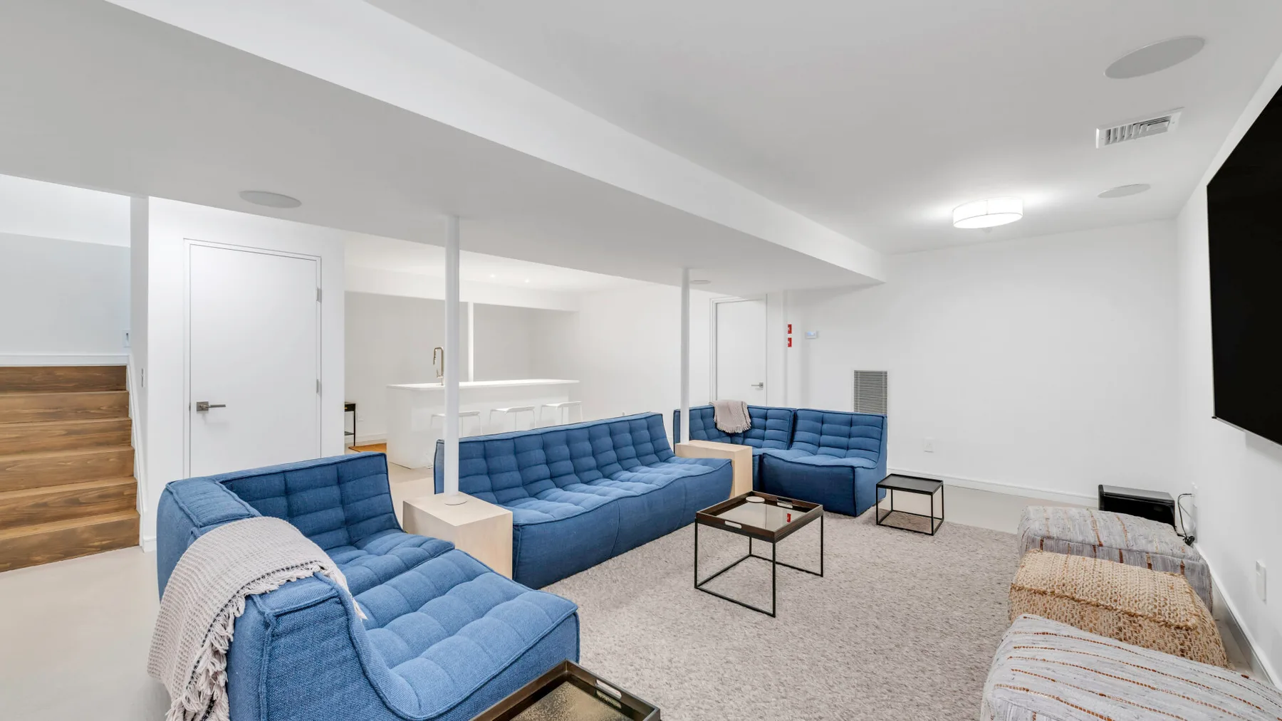 Una sala luminosa con asientos azules, mesas bajas y una pantalla en la pared.