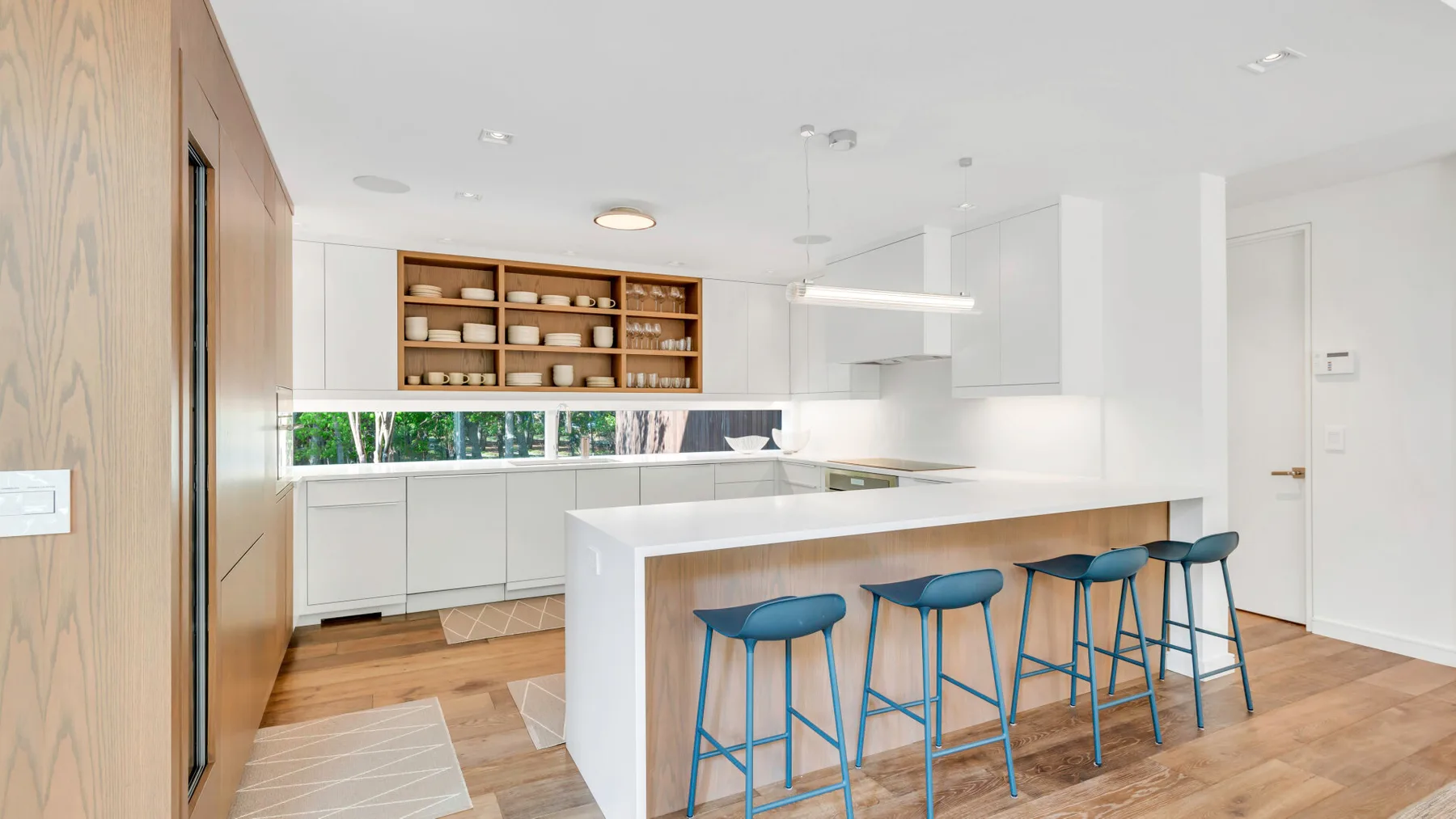 Una cocina luminosa con una isla larga y taburetes azules.