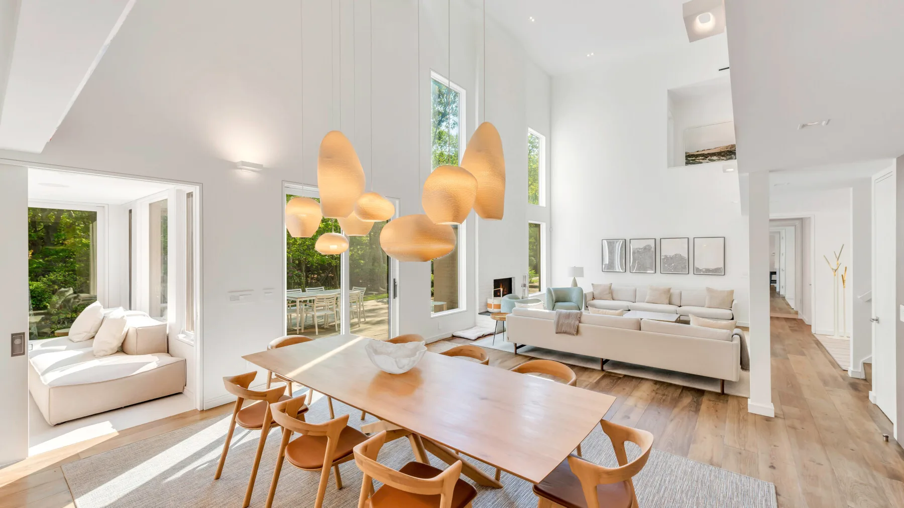 Una luminosa zona de comedor y sala de estar tiene una larga mesa de madera y asientos.