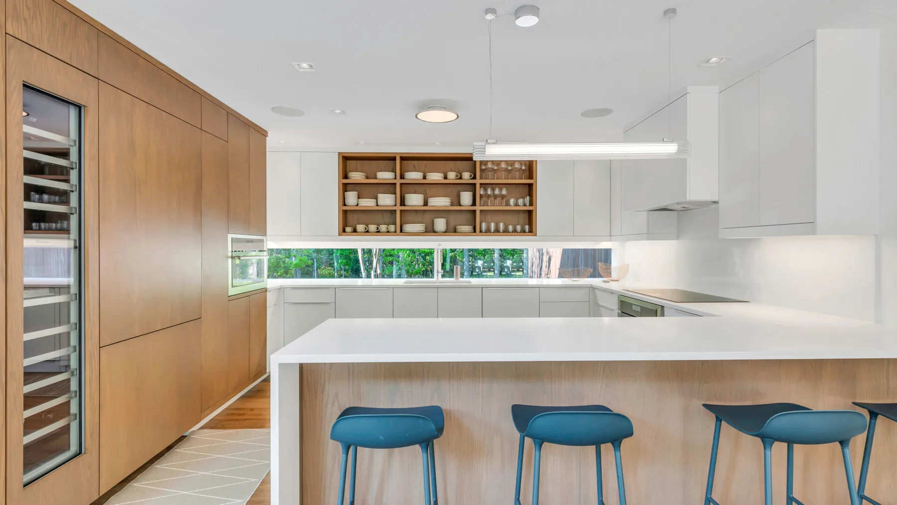 Una cocina moderna con una isla grande y taburetes azules.