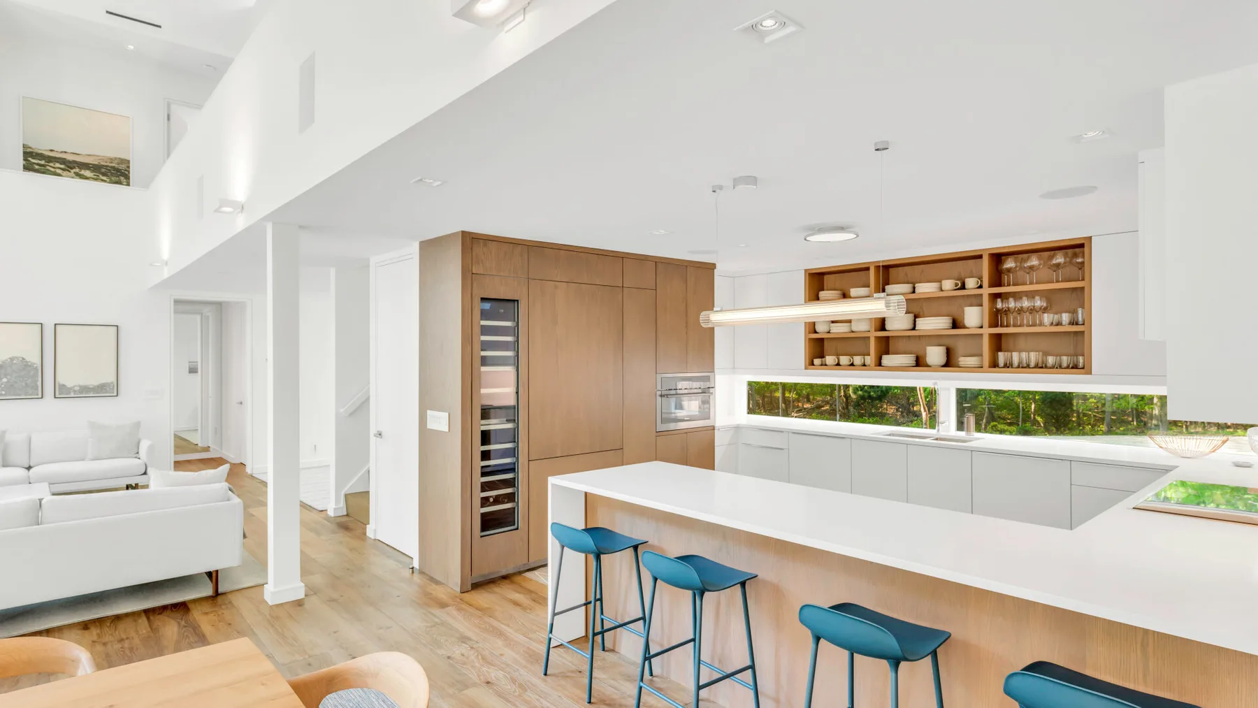 Cocina y sala de estar de concepto abierto con una barra larga y taburetes azules.