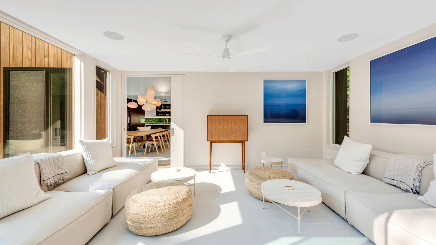 Una sala luminosa con asientos blancos y un puf tejido.