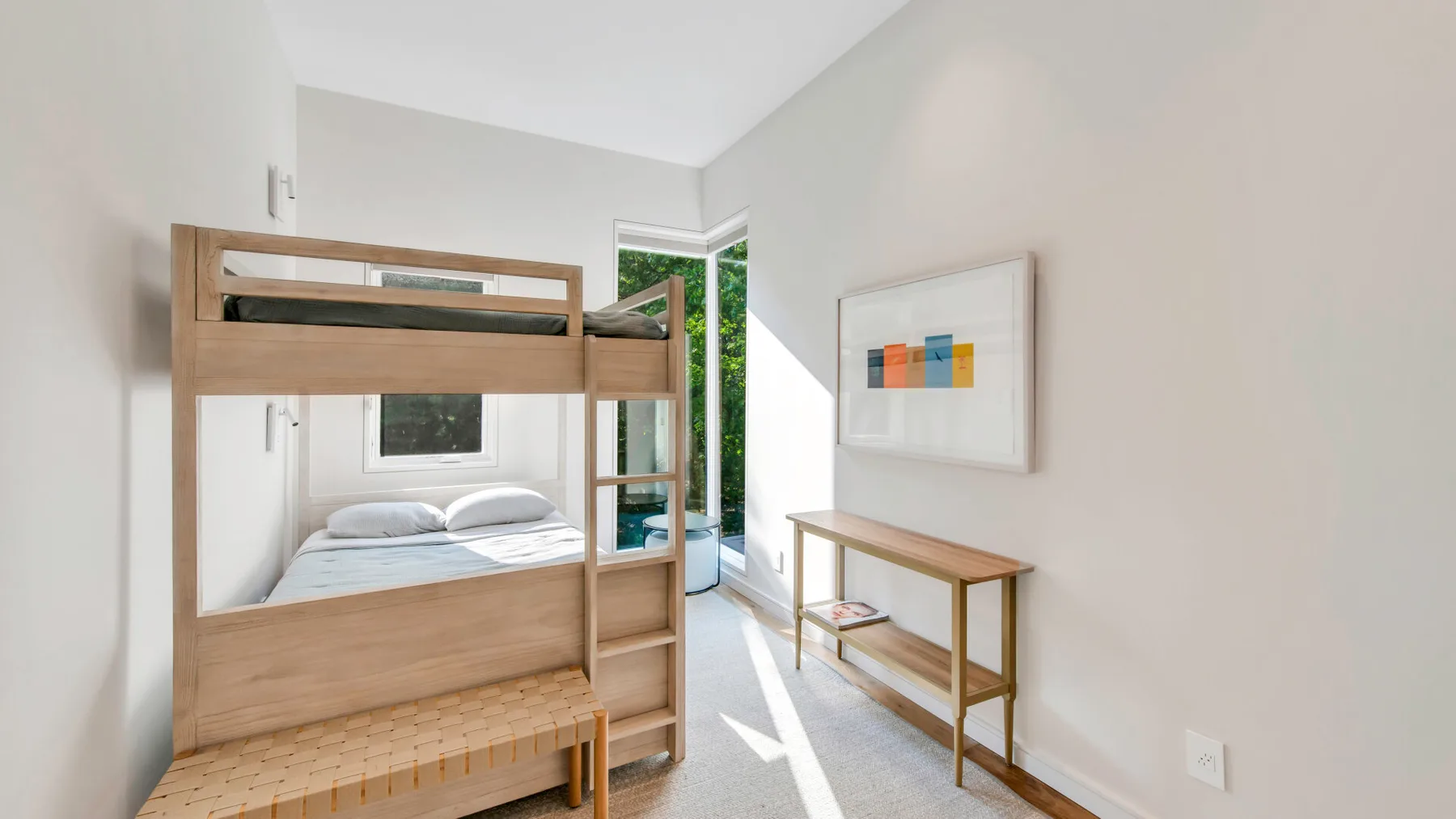Un dormitorio luminoso con una litera de madera y una cama bien tendida.