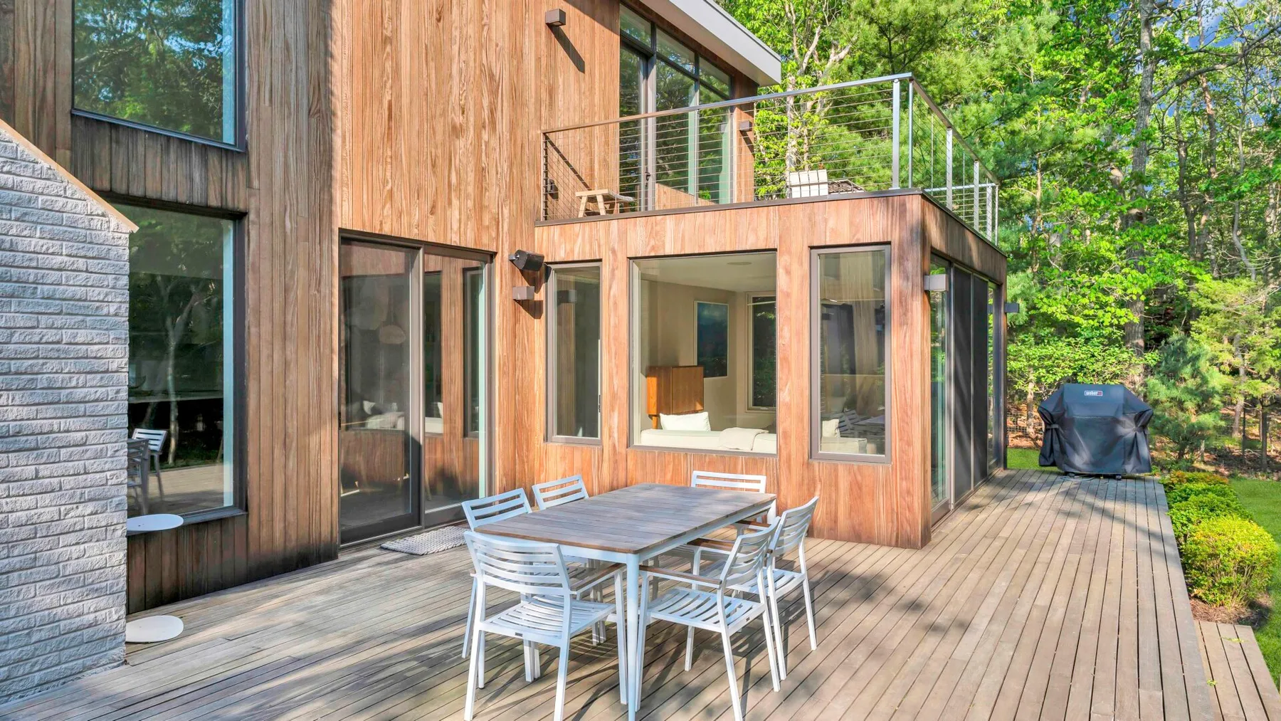 Una casa de madera da a una amplia terraza con una mesa de comedor al aire libre.