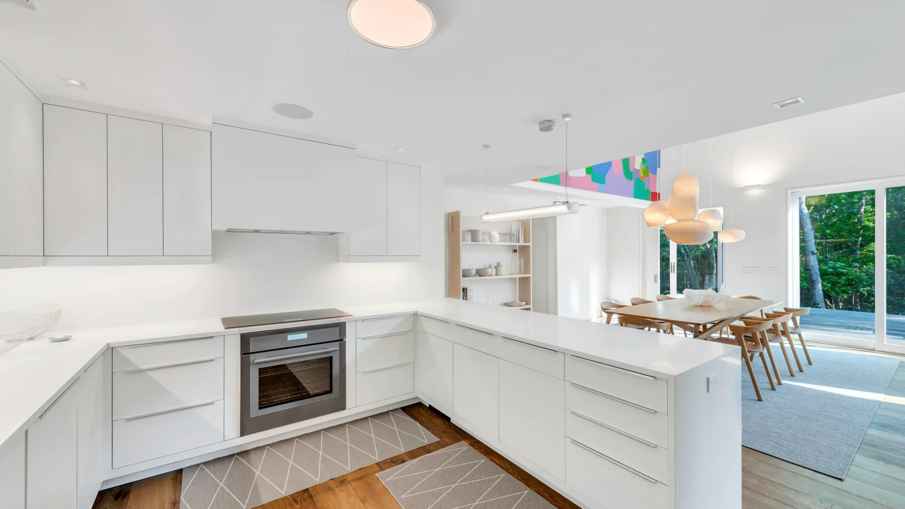 Una cocina blanca y luminosa con una isla central y una mesa de comedor.
