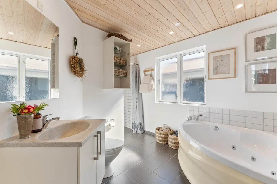 A bright bathroom with a bathtub, sink, and windows.