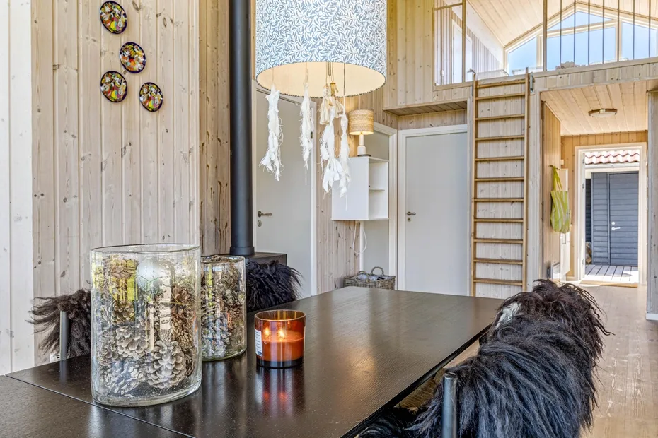 A wood-paneled interior with a dark table, hanging lamp, and ladder to a loft.