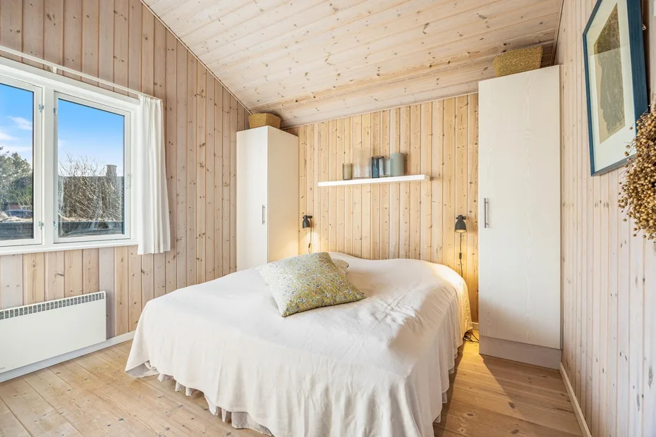 A bedroom with a bed, two wardrobes, and a window.
