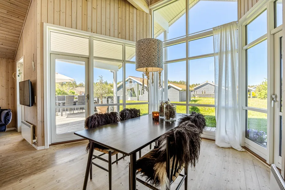 A bright dining area with a table beside large windows overlooking the garden.