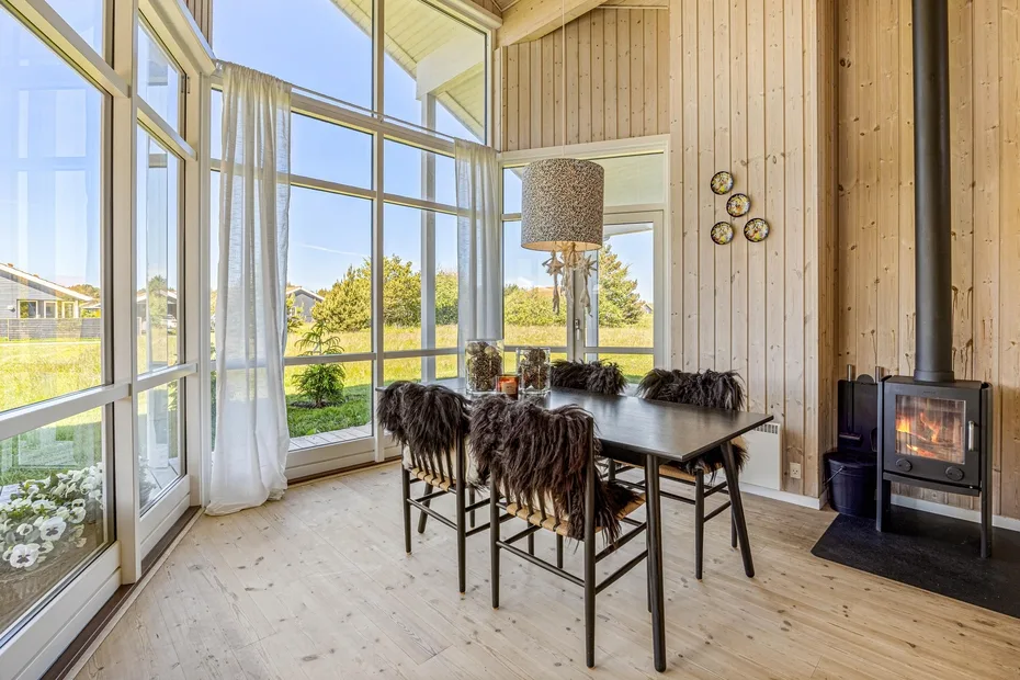 A dining area with a table and chairs beside large windows.