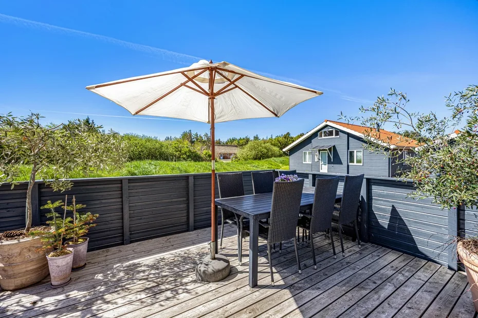 A rooftop deck has outdoor seating beneath a large patio umbrella.