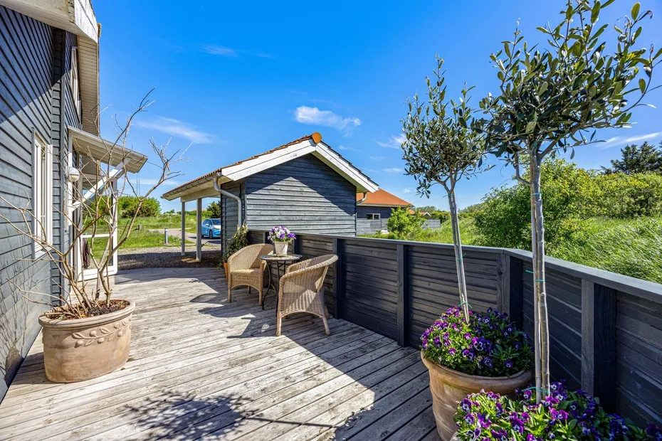 A wooden deck with outdoor seating and potted flowering plants.