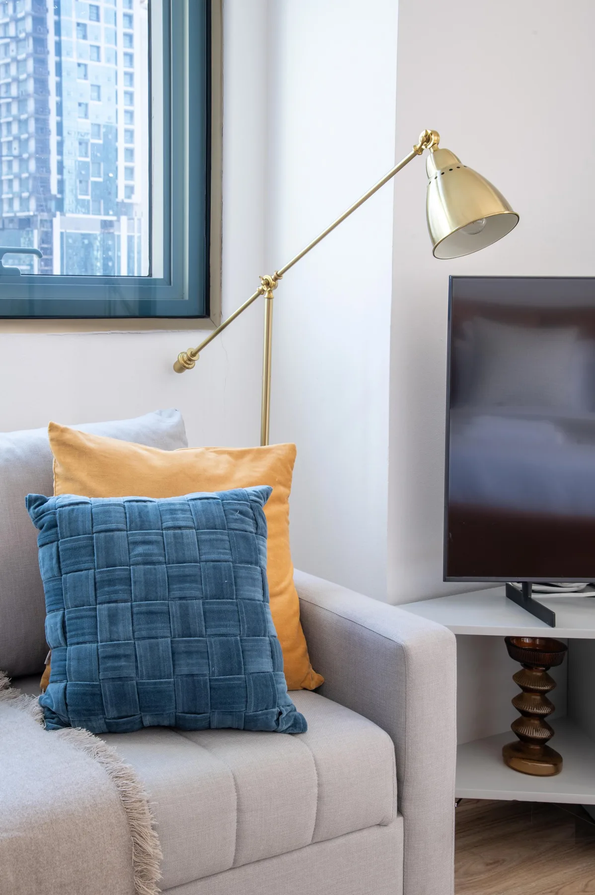 Una zona de estar con un televisor y una lámpara de pie de color dorado.