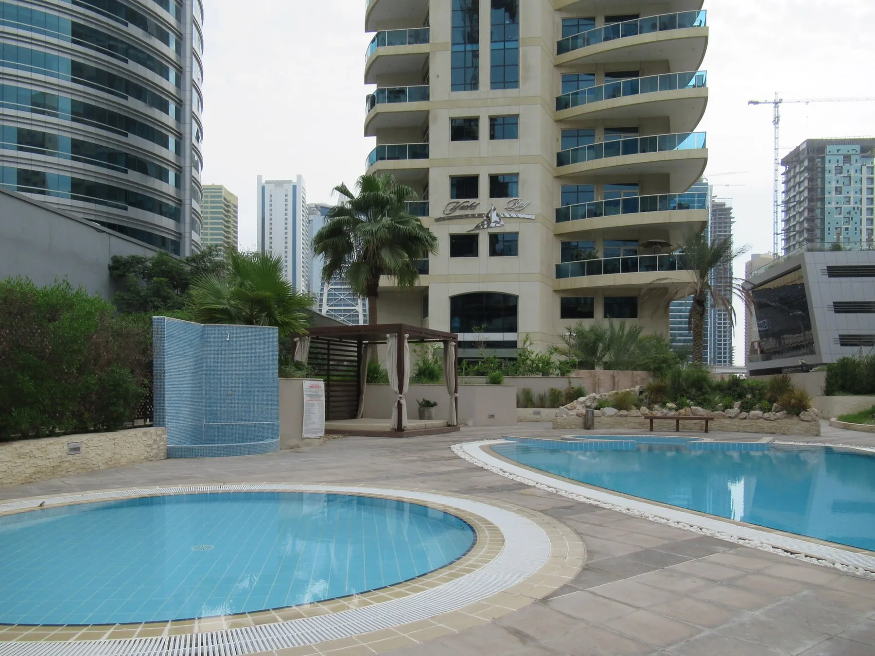 Piscinas al aire libre junto a jardines y edificios modernos de gran altura.