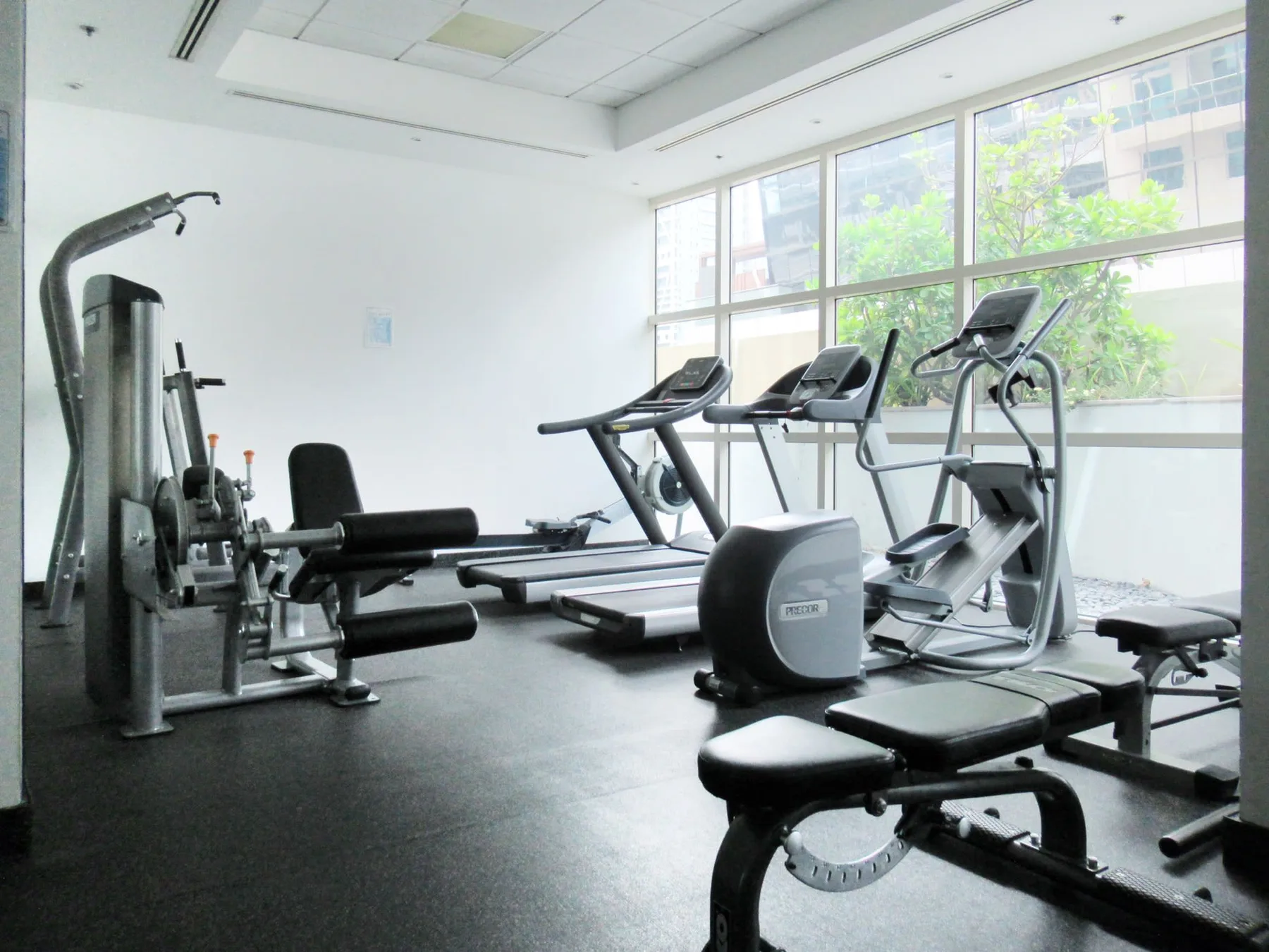 Un gimnasio luminoso con máquinas de ejercicio junto a grandes ventanales.