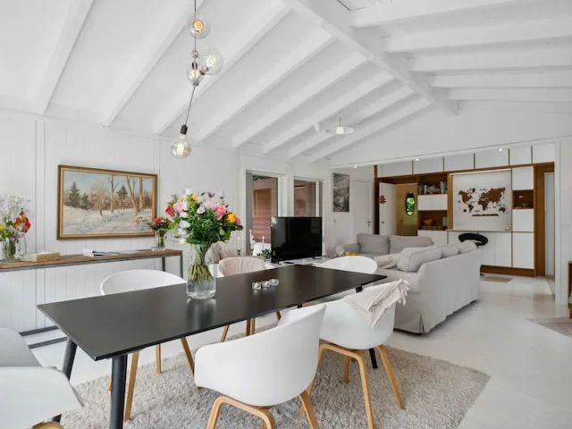 Bright living and dining room with a dark dining table and seating.