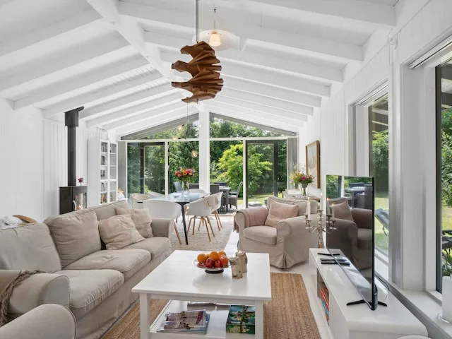 A bright living room with seating and a coffee table beside large windows.