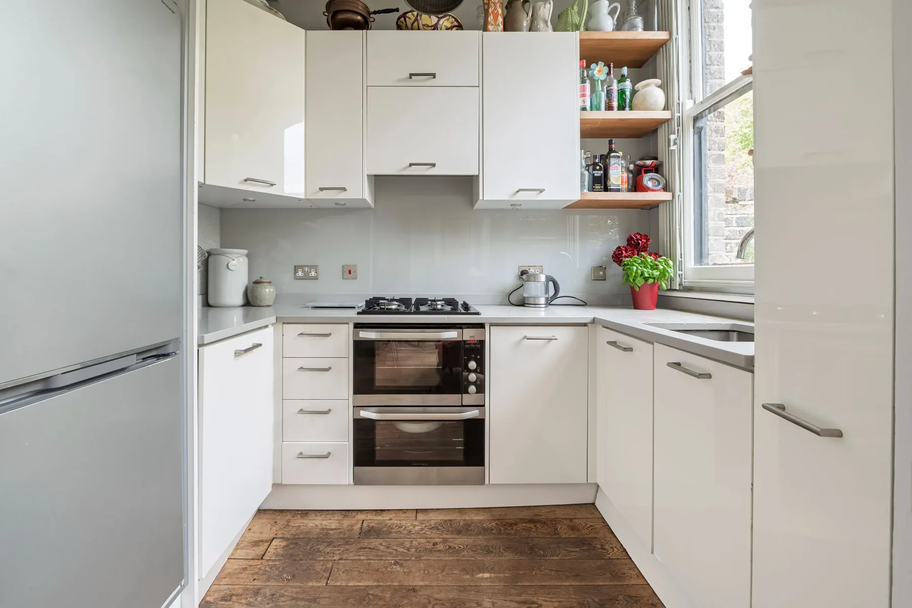 Una cocina compacta con armarios blancos, horno y una ventana.