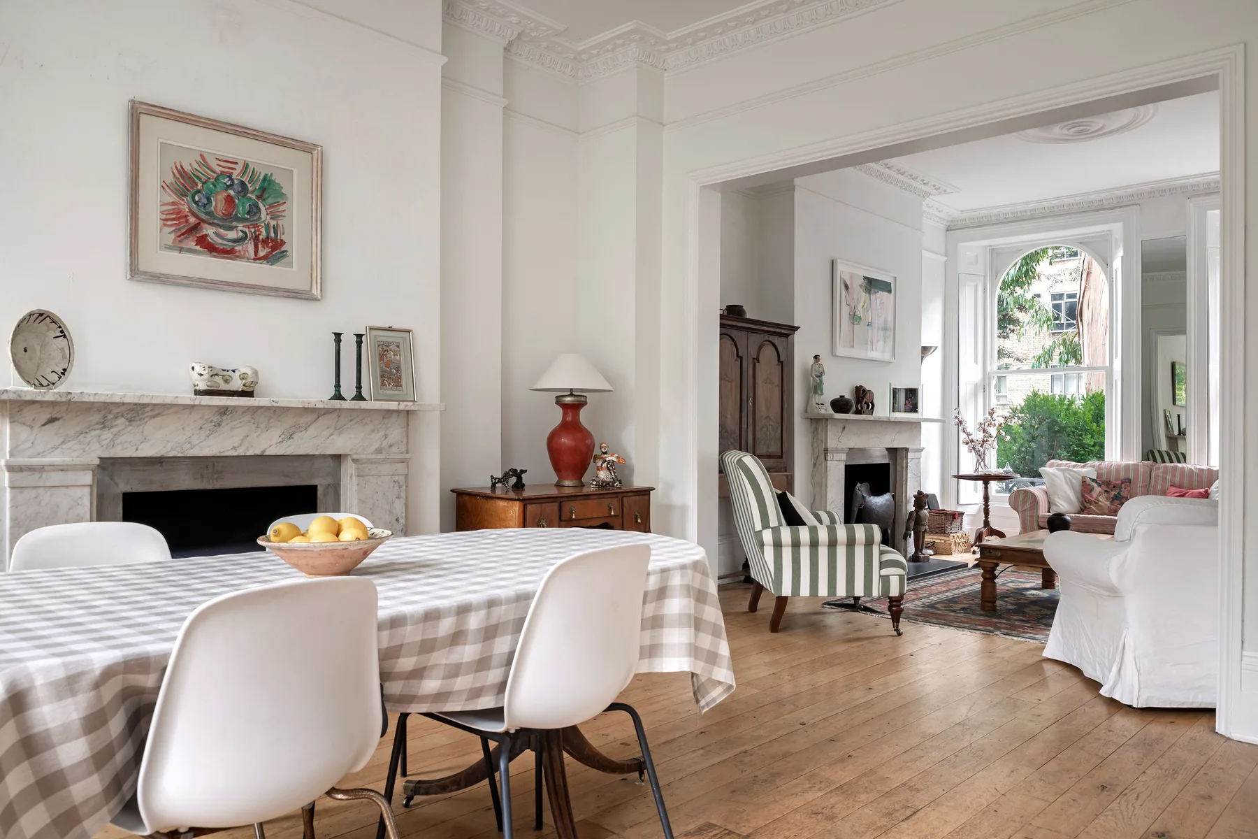 Un comedor luminoso se abre a una sala de estar con una gran ventana arqueada.