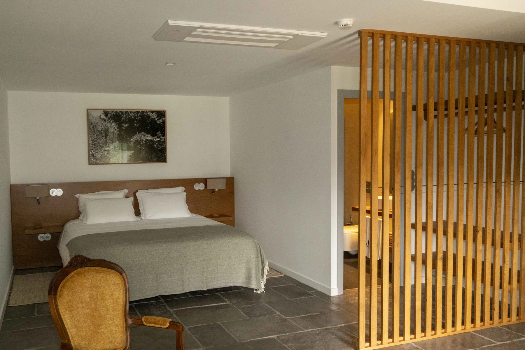 Un dormitorio con una cama y un separador de listones de madera.