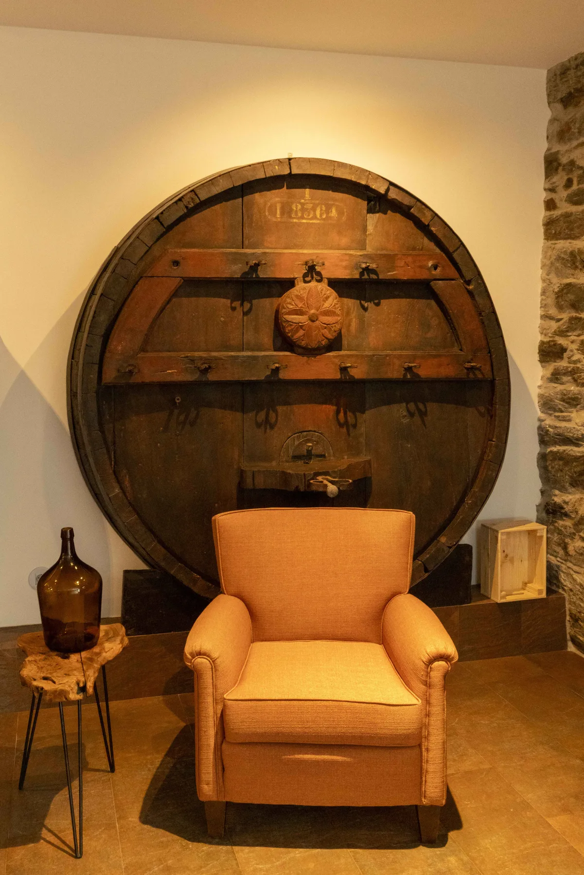 Una zona de descanso tiene un sillón frente a un gran barril de madera.