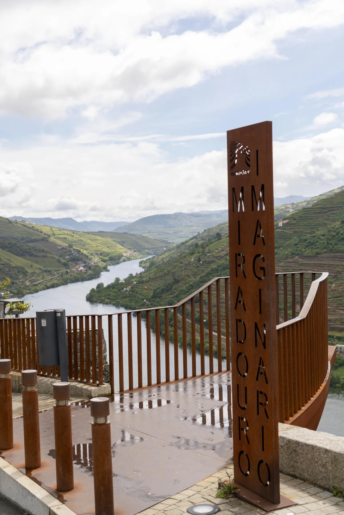 Una terraza junto al río ofrece vistas de un valle con colinas verdes y un río serpenteante.