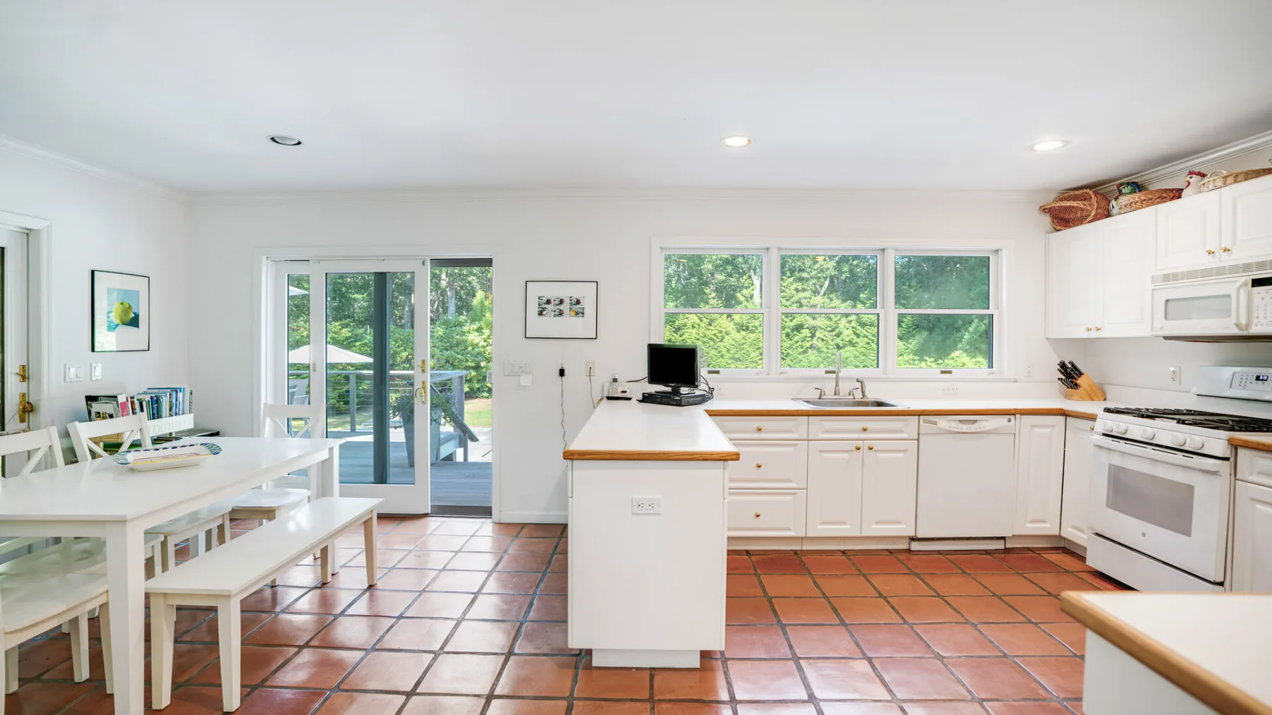 A bright kitchen with a central island, dining table, and large windows.