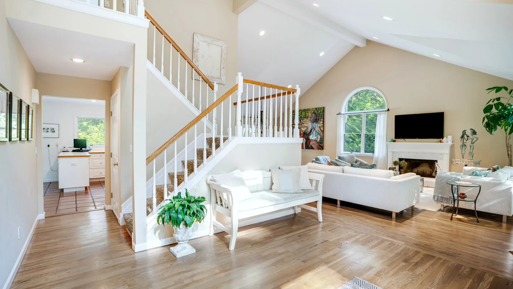 A bright living room with a staircase, seating, and a fireplace.