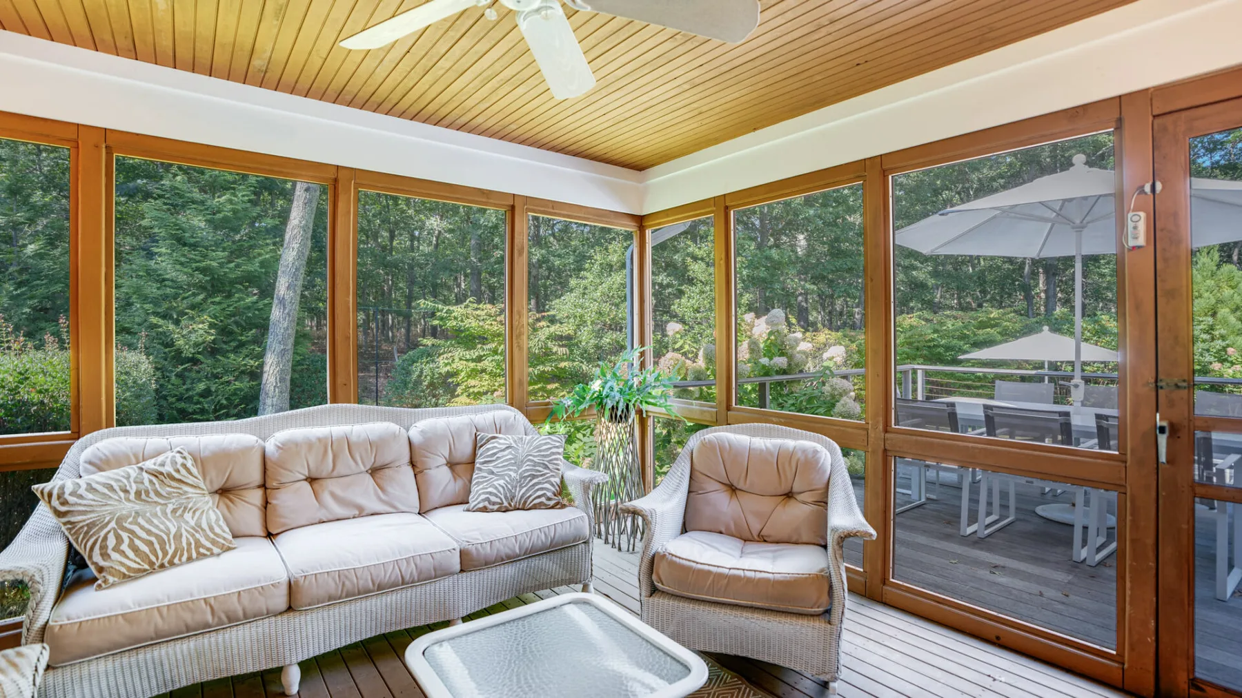 A sunroom with cushioned seating and large windows overlooking greenery.