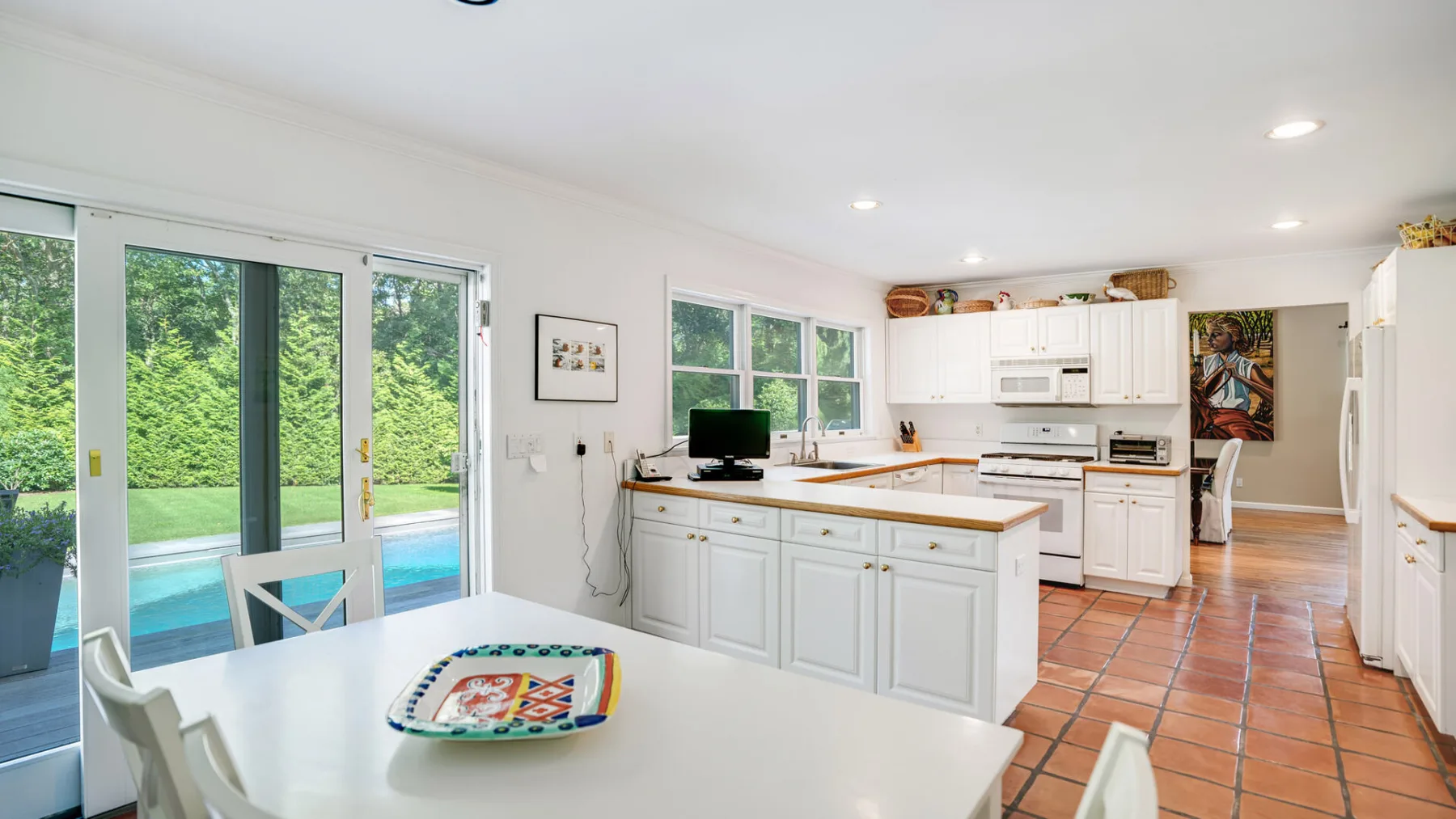 A bright kitchen and dining area opens onto a patio through large glass doors.