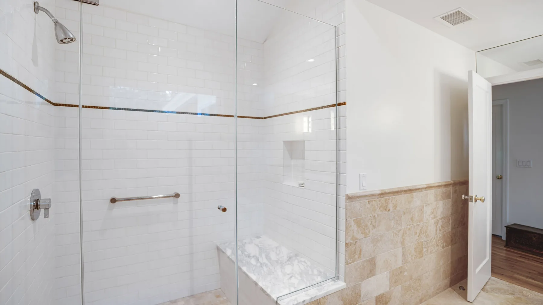 A bright bathroom with a glass shower and tiled walls.