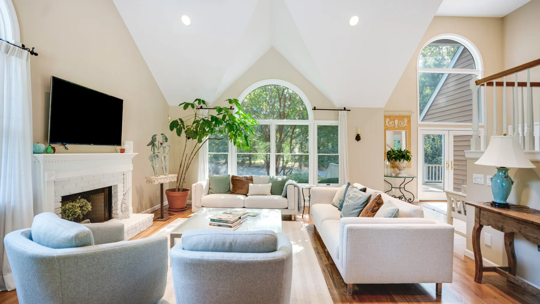 A bright living room with seating arranged around a fireplace and large windows.