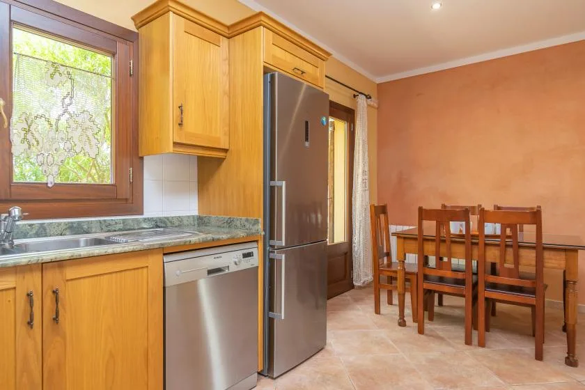 A kitchen and dining area with wooden cabinets, a refrigerator, and a dining table.