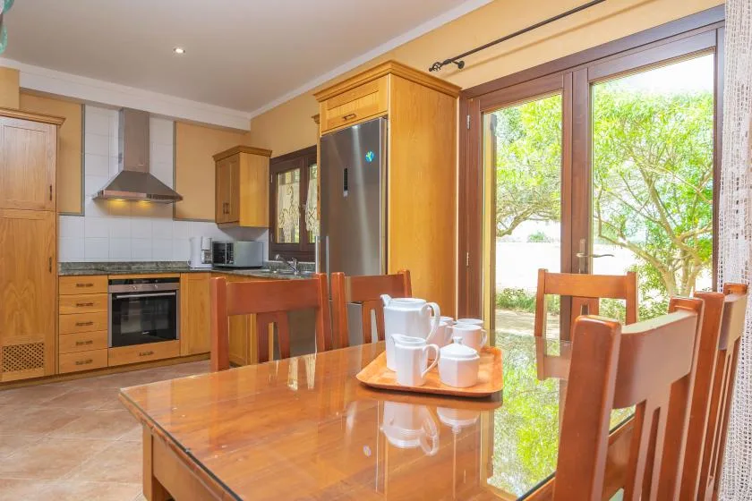 A kitchen and dining area with wooden seating beside large glass doors.