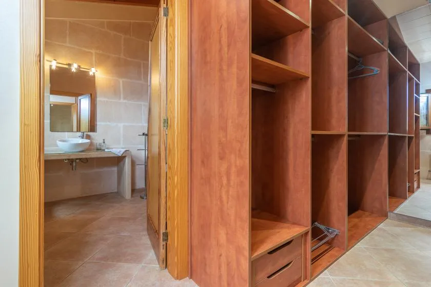 A dressing area with open wooden storage shelves beside a bathroom.