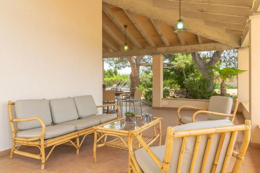 A covered patio with cushioned seating and a view of the garden.