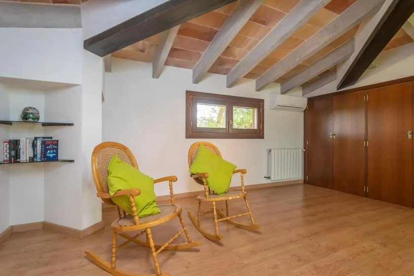 A bright room with exposed ceiling beams, wooden flooring, and two chairs.