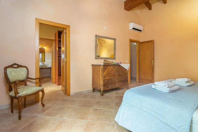 A bedroom with a bed, wooden dresser, and chair.